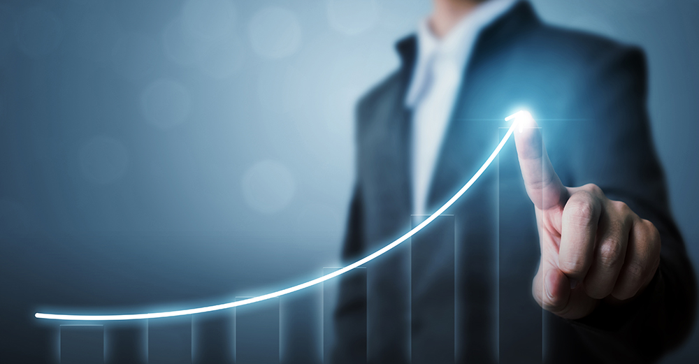 Businessman highlighting company increase with imaginary graph pointing to blue line going upwards.