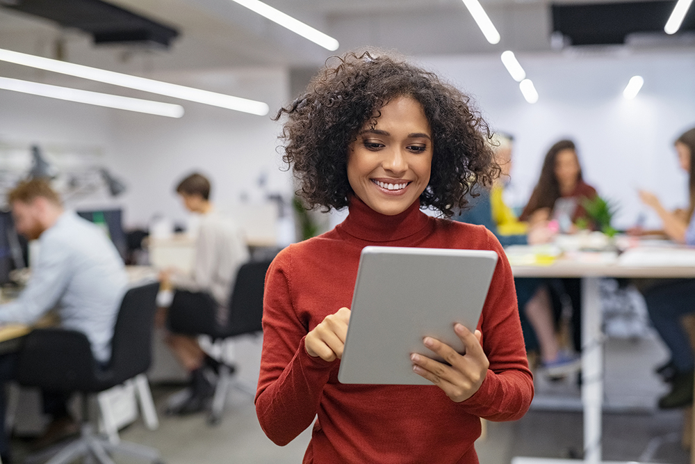 Happy woman using tablet in busy office.
