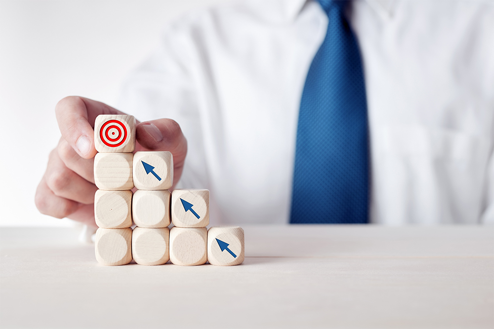 Businessman setting steps to reach a goal using dice blocks.