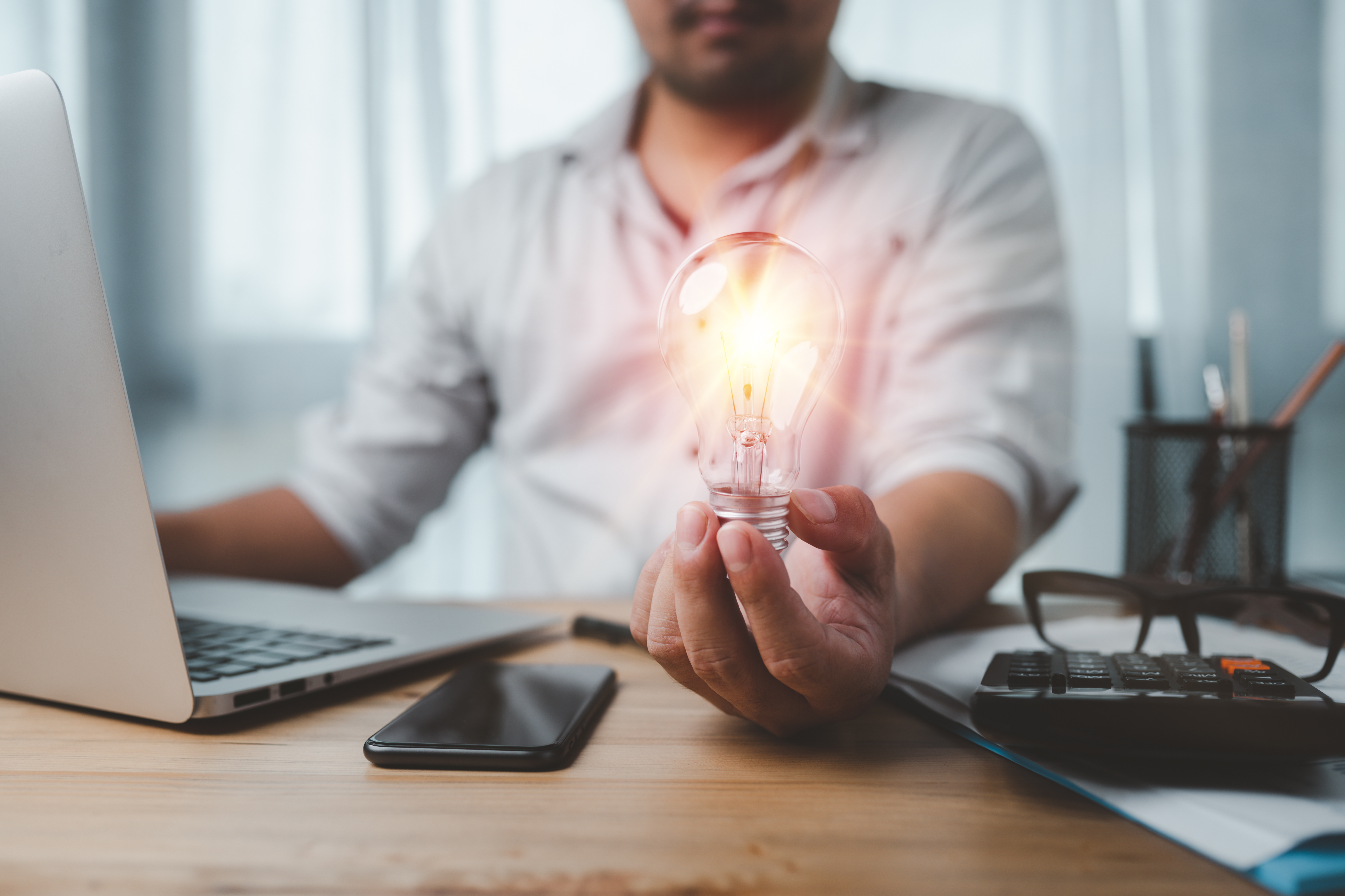 Innovative online technology idea concept. businessman holding lightbulb at office desk.