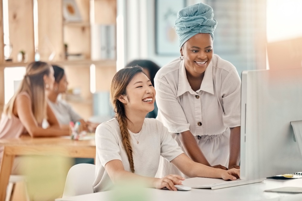 Diversity, help or training at computer in office brainstorming idea with smiles. Asian and black woman