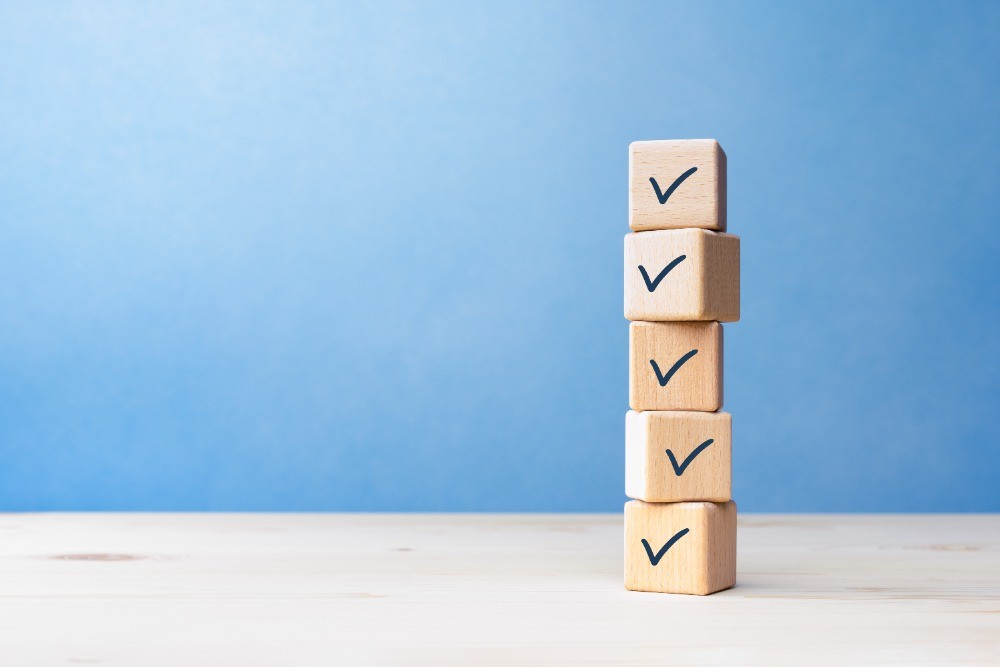 Pile of wooden cubes with check symbols on desk with blue background.