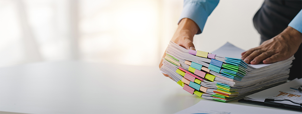 Businessman holding stack of paper sectioned with colourful clips.