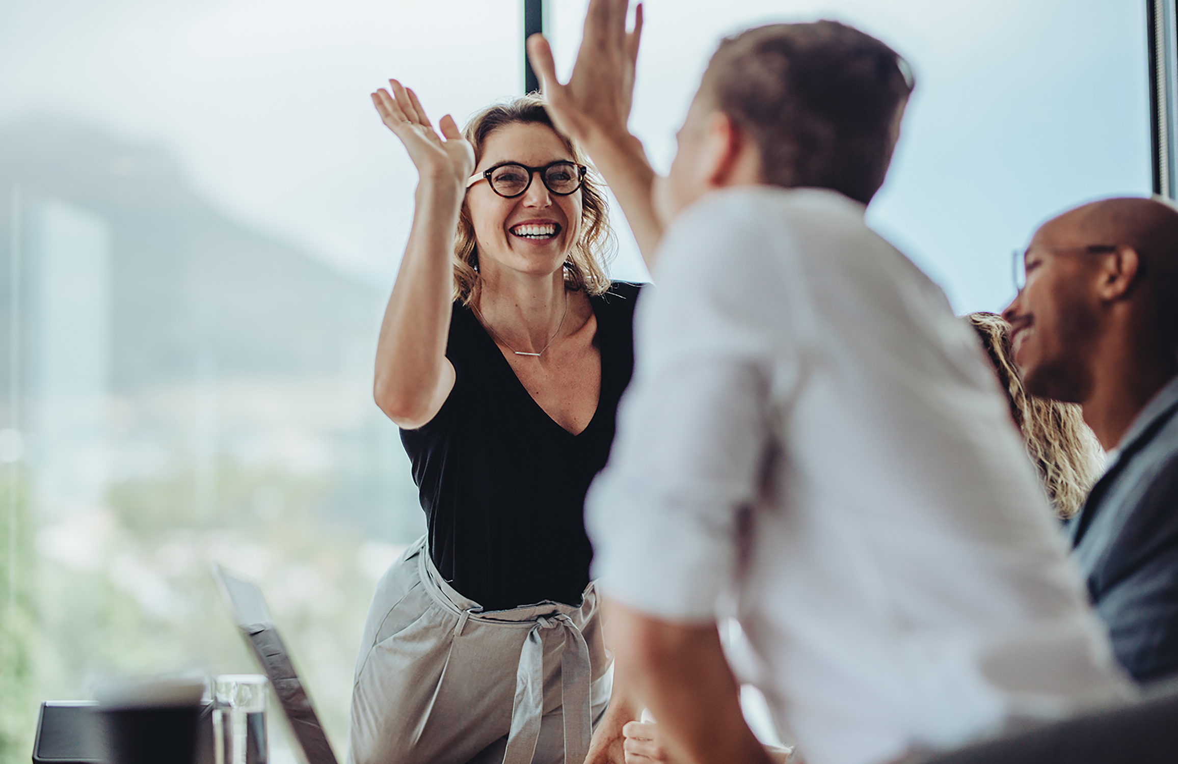 Pretty businesswoman giving a high five to a colleague in meeting