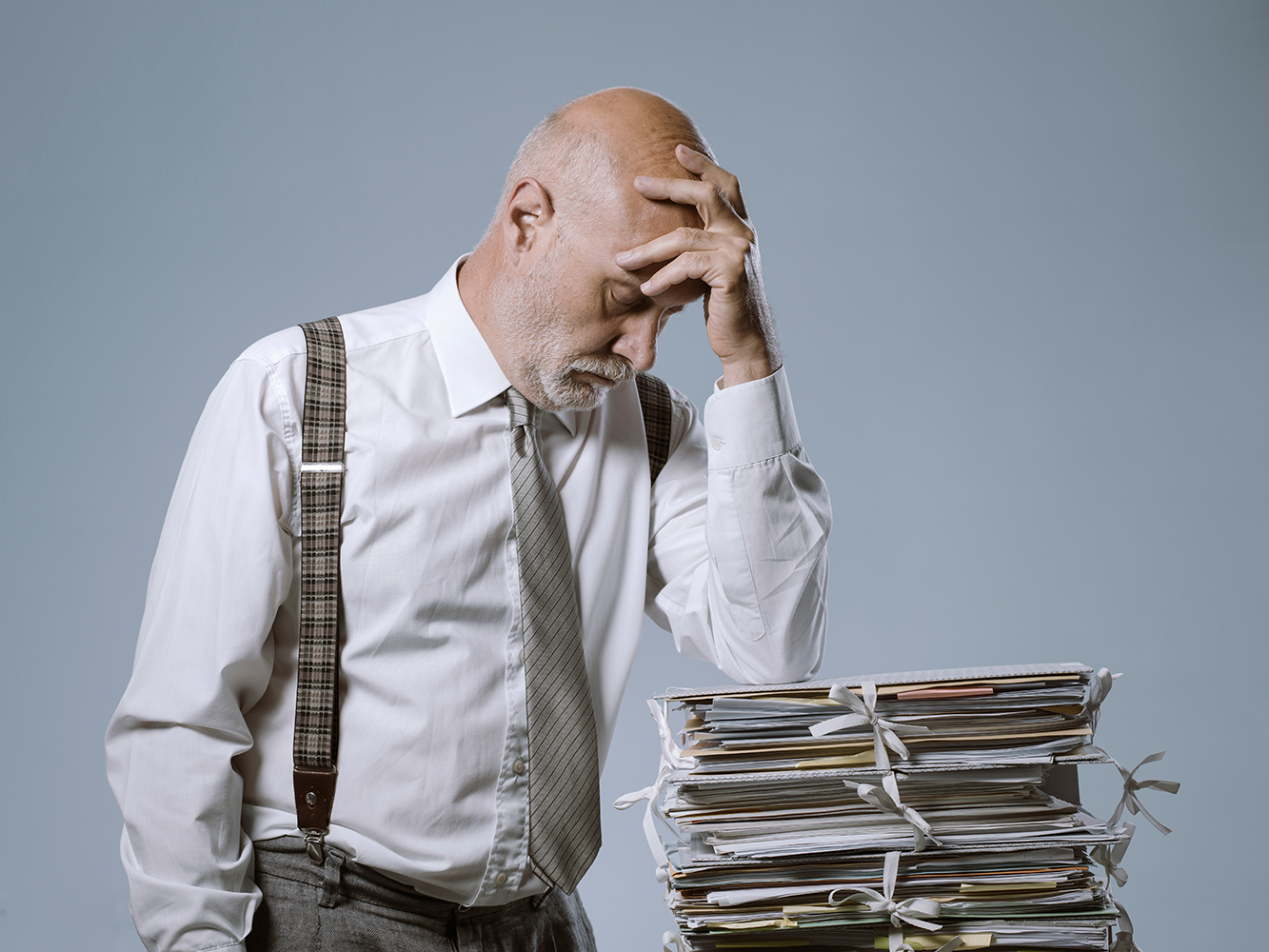 Pensive businessman leaning on a pile of paperwork