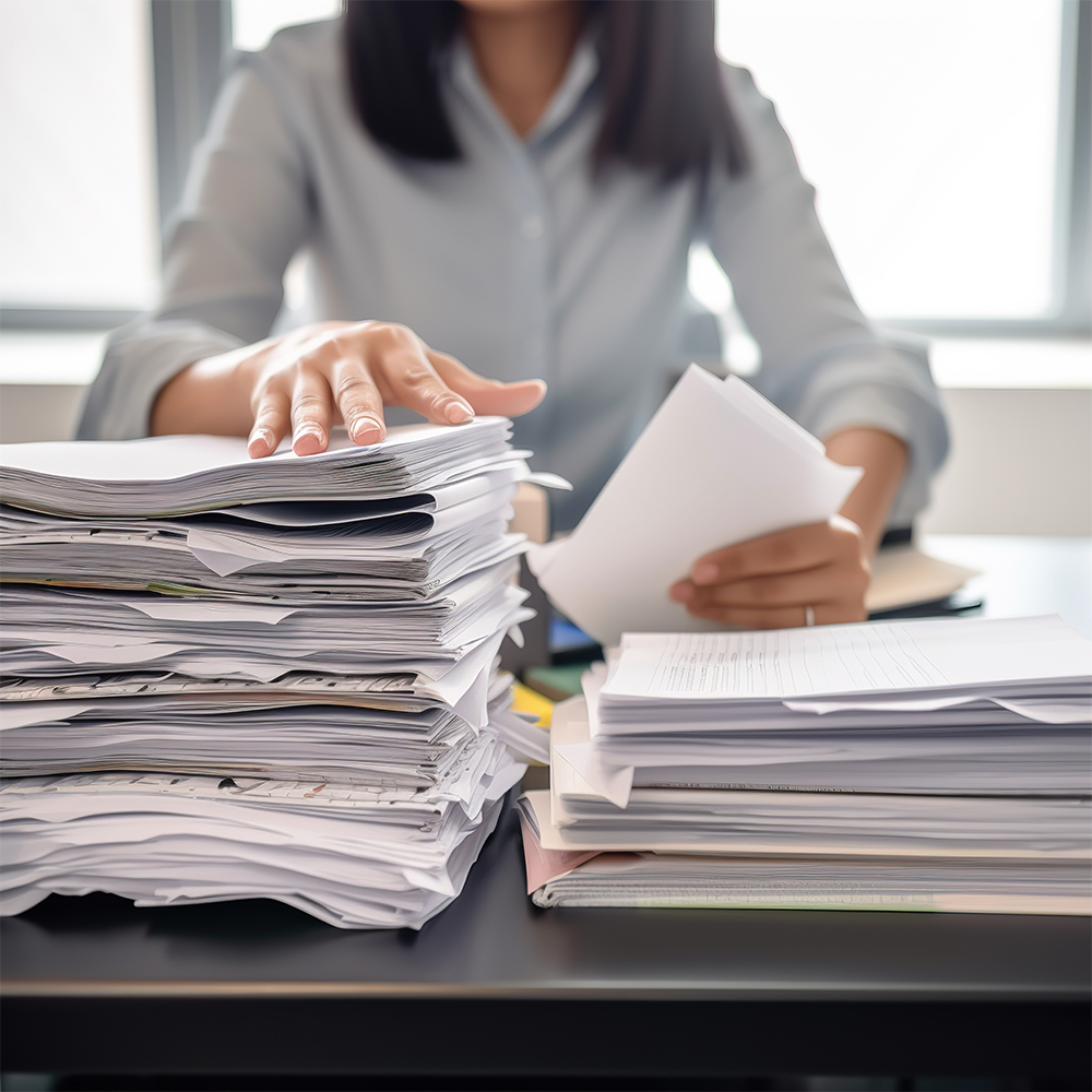 Hard working office woman working with piles of documents.